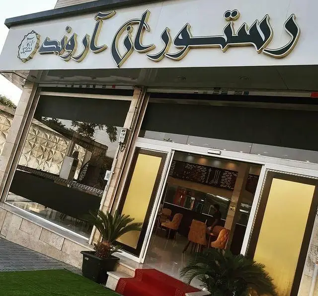 تصویر نمای بیرونی و ورودی اصلی رستوران آروند با تابلوی بزرگ و جذاب، درب‌های شیشه‌ای مدرن و فرش قرمز در انتظار مهمانان.