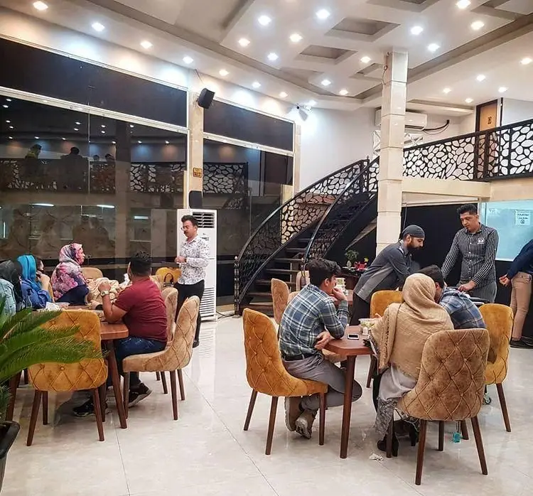 فضای داخلی رستوران آروند با مشتریان در حال صرف غذا، میز و صندلی‌های شیک، راه‌پله دکوراتیو و نورپردازی مدرن.