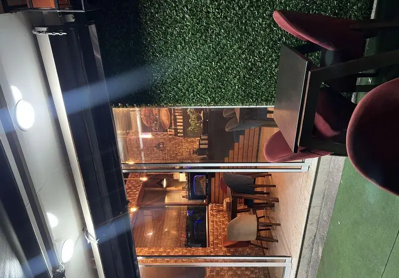 فضای باز فست فود گریل لند با دیوارهای سبز و دکوراسیون آجری داخلی، میز و صندلی‌های راحت، محیطی دلنشین برای مشتریان.