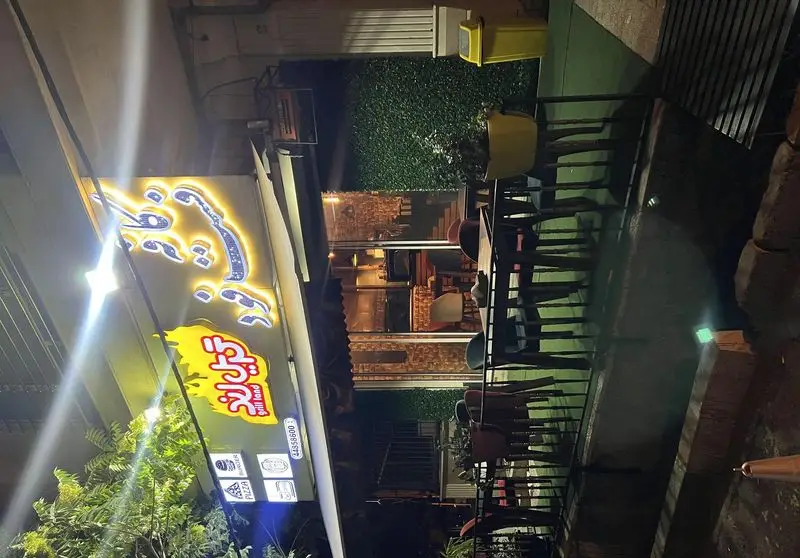 تصویر شب از فست فود گریل لند با نورپردازی جذاب، تابلوی روشن، فضای غذاخوری بیرونی با میز و صندلی و سرویس پیتزا و برگر.