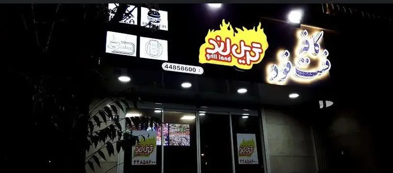 تصویر شبانه از تابلوی نئونی فست فود گریل لند با لوگوی شعله‌ای، نام فارسی و انگلیسی، و شماره تماس 44858600 بر روی سردر یک رستوران.