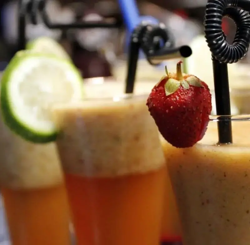نوشیدنی‌های خنک و میوه‌ای کافه جاپا: اسموتی‌های تازه با لایه بندی زیبا، تزئین شده با توت فرنگی و برش لیمو.