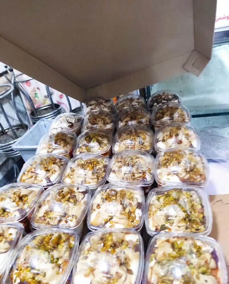 نمایی از دسرهای خوشمزه آبمیوه شهریور شامل بستنی و کرم با روکش پسته و انواع آجیل تازه و مرغوب، آماده برای سفارش.