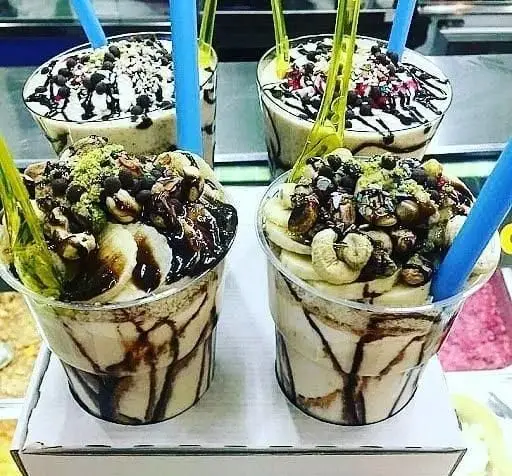 چند لیوان میلکشیک خوشمزه و خامه ای با موز تازه، مغزهای سالم (بادام هندی، فندق)، چیپس و سس شکلات تزیین شده در آبمیوه شهریور