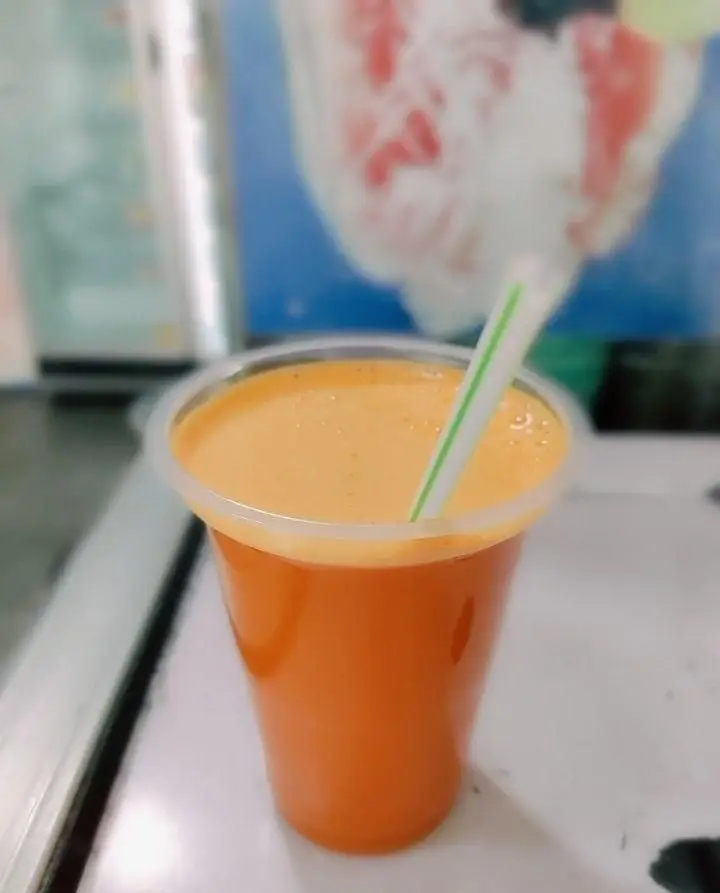 یک لیوان آبمیوه تازه و طبیعی با رنگ نارنجی دلنشین، همراه با نی، آماده برای نوشیدن. این نوشیدنی خنک و گوارا از آبمیوه شهریور است.