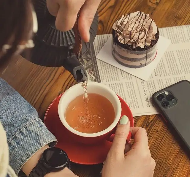 لحظه‌ای دلپذیر در کافه سرای ارغوان: چای گرم در حال سرو، در کنار کیک شکلاتی لذیذ و فضایی آرام برای تجربه‌ای شیرین.