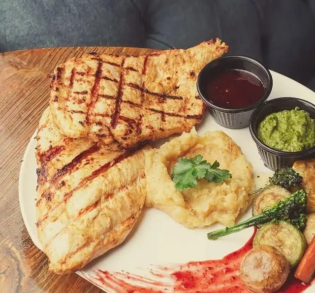 سینی مرغ گریل شده با پوره سیب‌زمینی، سبزیجات برشته و دو سس خوش‌طعم در کافه سرای ارغوان، غذایی دلپذیر برای شما.