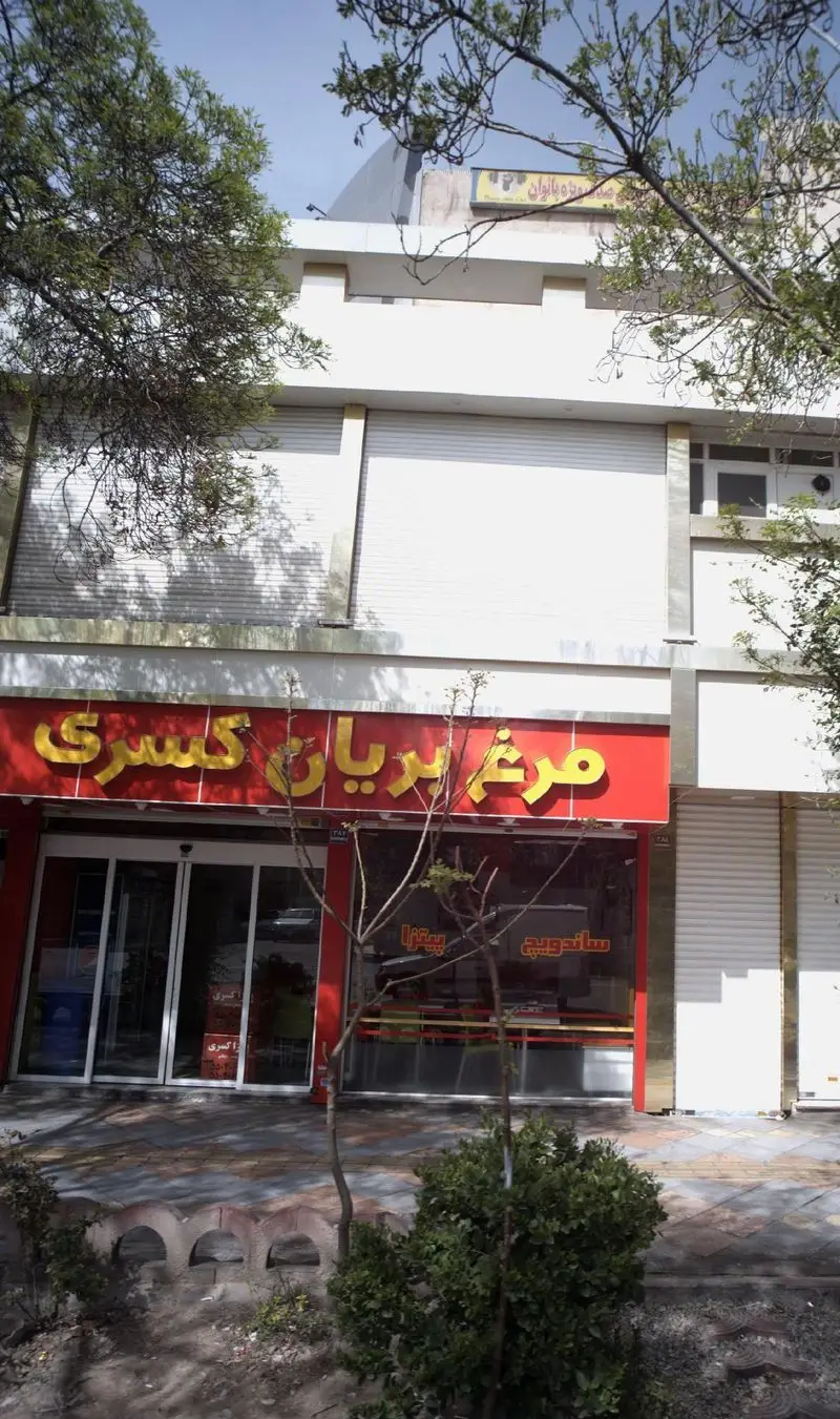 تصویر نمای بیرونی رستوران فست فود مرغ بریان کسری با تابلو قرمز درخشان، عرضه کننده مرغ بریان، پیتزا و انواع ساندویچ تازه.