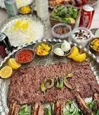 سفره کامل و جذاب از دنده کباب رستوران طاق بستان با برنج زعفرانی، انواع ترشی، ماست، لیمو و نوشیدنی‌های خنک.