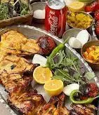 سفره آرایی دلنشین و غذای ویژه رستوران دنده کباب طاق بستان؛ شامل سینی بزرگ جوجه کباب، لیمو، سبزیجات تازه، نوشابه و مخلفات خوشمزه.