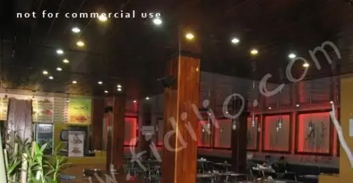 تصویری از داخل فست فود باگت، محیطی مدرن با نورپردازی گرم، میز و صندلی‌های راحت، و دکوراسیون زیبای دیوارهای قرمز رنگ.