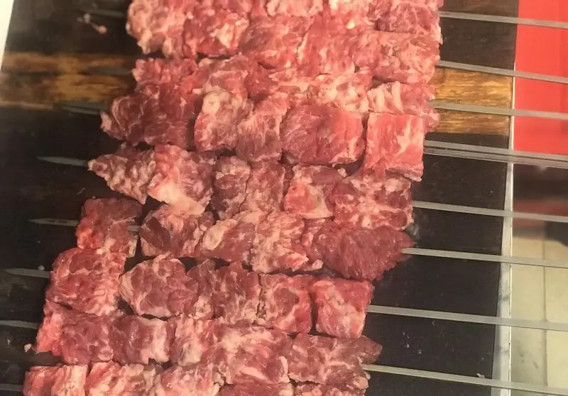 آماده‌سازی گوشت تازه و برش‌خورده روی سیخ برای طبخ کباب‌های مخصوص و خوشمزه جگرسرای نیلوفر. کیفیت عالی و طعم بی‌نظیر.
