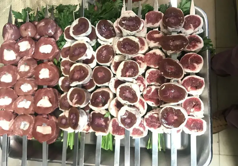 سیخ‌های کباب جگر، دل، قلوه و تکه‌های گوشت تازه با چربی، مرتب چیده شده و آماده طبخ در جگرسرای نیلوفر. انتخابی عالی.