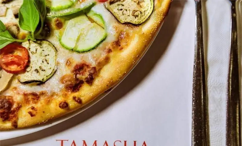 پیتزا سبزیجات لذیذ رستوران تماشا با تاپینگ‌های تازه کدو، بادمجان، گوجه و ریحان، همراه کراست طلایی و ترد، یک غذای ایتالیایی عالی.