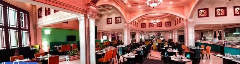 تصویر فضای داخلی زیبای رستوران تماشا با معماری قوسی، میزهای غذاخوری آماده و بخش بوفه متنوع برای مشتریان.