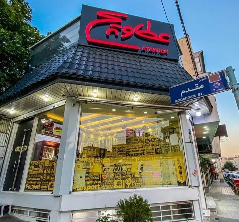 نمای خارجی فست فود عطاویچ در خیابان مقدم تهران با تابلوی بزرگ ATAWICH و ویترین های شیشه‌ای طرح‌دار برای جذب مشتری.