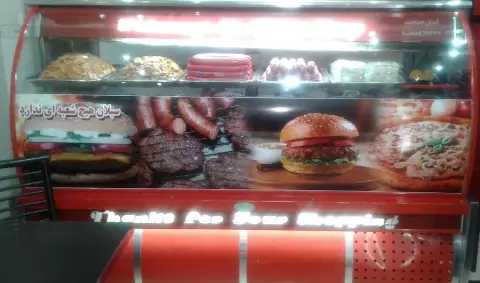 ویترین روشن پیتزا سبلان با نمایش جذاب پیتزا، همبرگر، سوسیس و کباب. تنوع محصولات فست فود و غذای آماده.