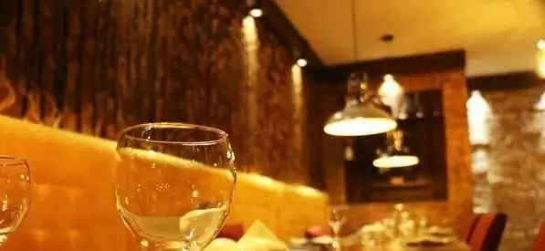 نمایی دلنشین از دکوراسیون داخلی رستوران فرنگی نعنا با نورپردازی گرم، میزهای چیده شده و لیوان‌های شیشه‌ای برای تجربه‌ای لذت‌بخش.