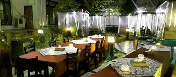 فضای باز و دلنشین کافه ایل بختیاری در شب، با چیدمان میز و صندلی‌های سنتی، نورپردازی گرم و محیطی آرام برای مشتریان.