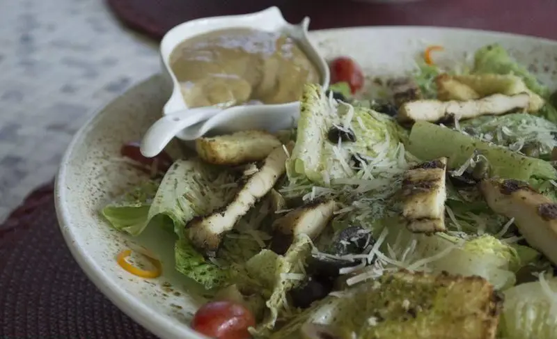 سالاد سزار مرغ گریل شده وتوس: ترکیبی لذیذ از کاهو تازه، کروتون، پنیر پارمزان، زیتون، گوجه و سس مخصوص. غذای سالم و خوشمزه.