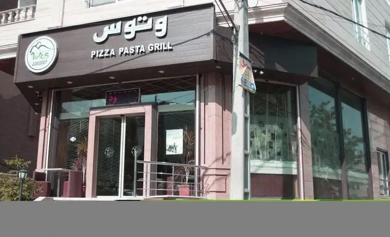 عکس نمای بیرونی مغازه رستوران وتوس (Vetus) با تابلوی روشن PIZZA PASTA GRILL، لوگوی برند و شماره تلفن 22802007.