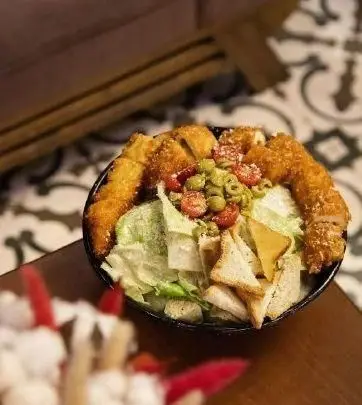 سالاد مرغ سوخاری کافه نان روتی، شامل کاهوی تازه، زیتون، گوجه گیلاسی و نان تست برشته با فیله مرغ ترد و طلایی.