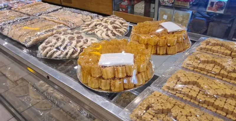 ویترین شیرینی سرای پاک با انواع شیرینیهای تازه و خوشمزه، شامل کوکیها، شیرینیهای عسلی و دسرهای سنتی ایرانی.