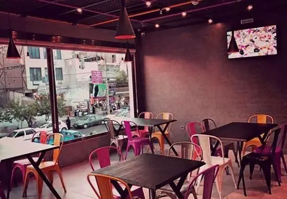 فضای داخلی شیک رستوران ایتالیایی آرت گریل با دکوراسیون مدرن، میزهای تیره، صندلی‌های فلزی رنگارنگ و نمای زیبای خیابان شهر.