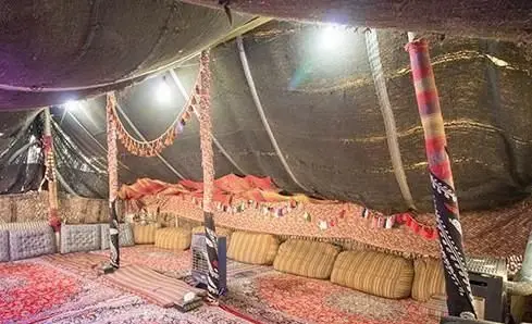 محیط سنتی و دنج سیاه چادر در رستوران و کافه باغ مشیر، با فرش‌های زیبا و پشتی‌های راحت برای تجربه آرامش‌بخش.