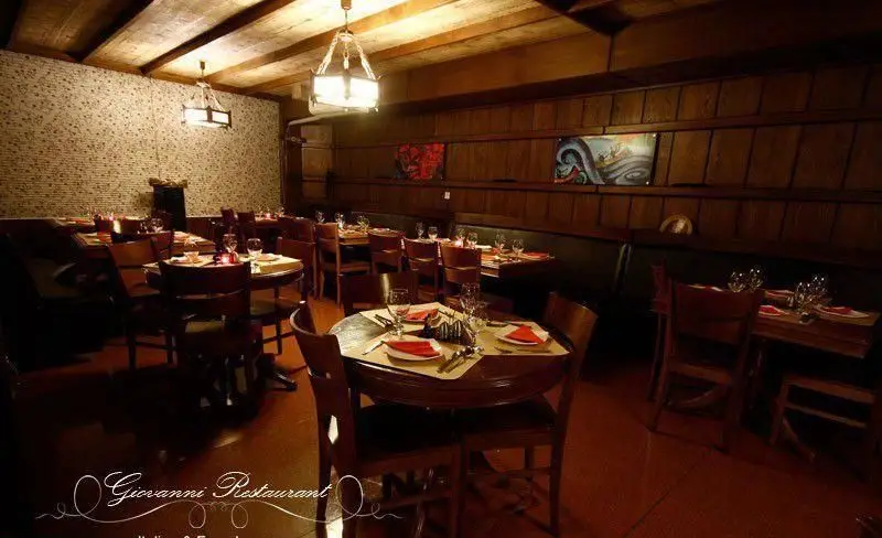 فضای داخلی رستوران ایتالیایی جنارو با دکوراسیون چوبی، میزهای چیده شده، نورپردازی خاص و محیطی دلنشین آماده پذیرایی.