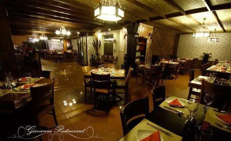 فضای داخلی دنج و شیک رستوران ایتالیایی جنارو با میزهای چوبی، سقف تیرکوبی شده و لوسترهای گرم برای مهمانان.