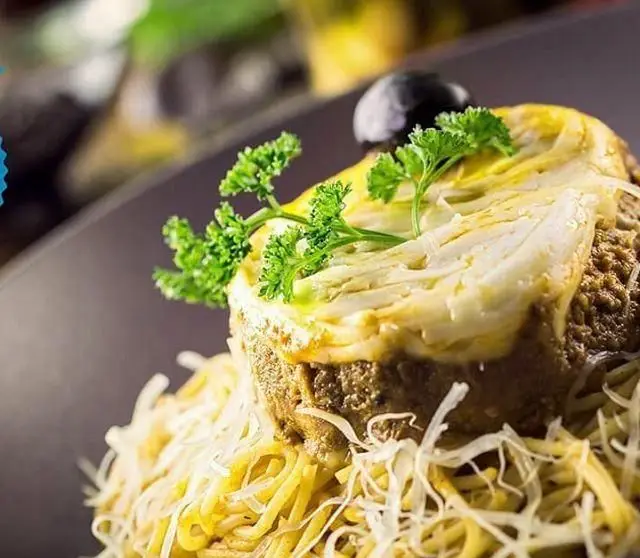 پاستا با غذای گوشتی قالبی و پنیر آب شده، مزین به جعفری و زیتون، یک شاهکار خوشمزه از منوی رستوران ایتالیایی جنارو.