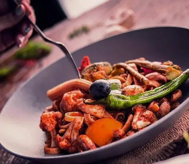 غذای پاستای خانگی و خوشمزه در محیط دلنشین رستوران ایتالیایی جنارو. شامل قارچ‌های متنوع، فلفل سبز، زیتون و سس لذیذ.