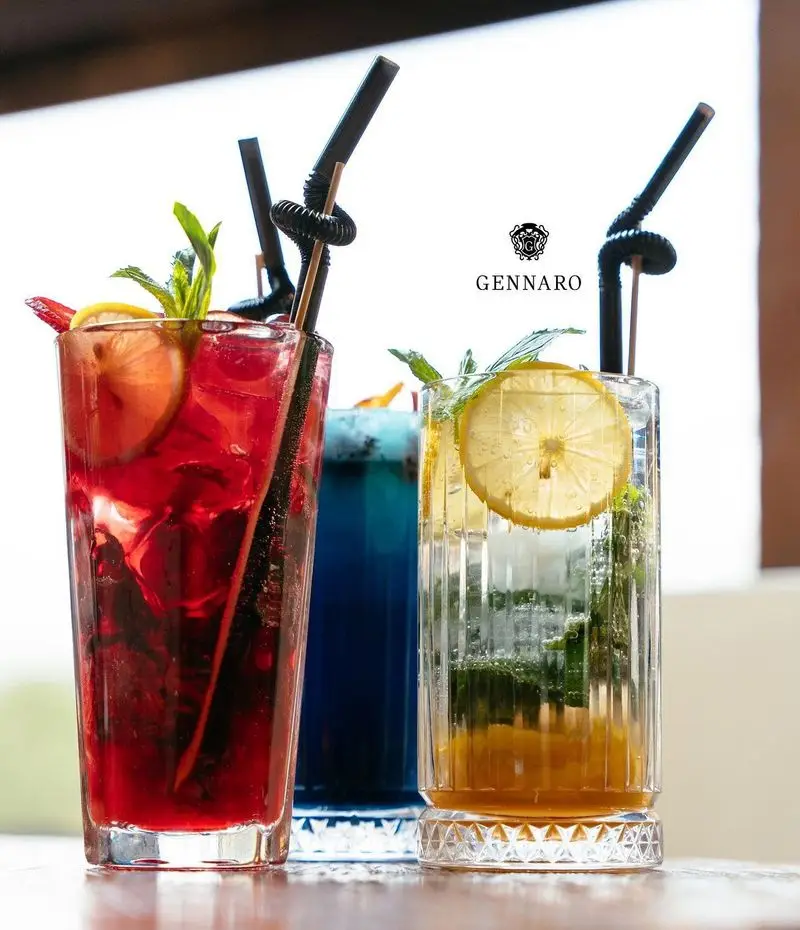 تصویری از سه نوشیدنی خنک و رنگارنگ (قرمز، آبی، زرد) با تزئینات لیمو، نعنا و توت فرنگی در رستوران ایتالیایی جنارو.