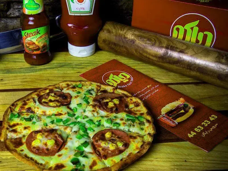 تصویر از پیتزا لذیذ و پرملات فست فود دیاکو، همراه با سس کچاپ و سس استیک. منوی متنوع غذای آماده، سرویس رایگان و شماره تماس جهت سفارش آسان.