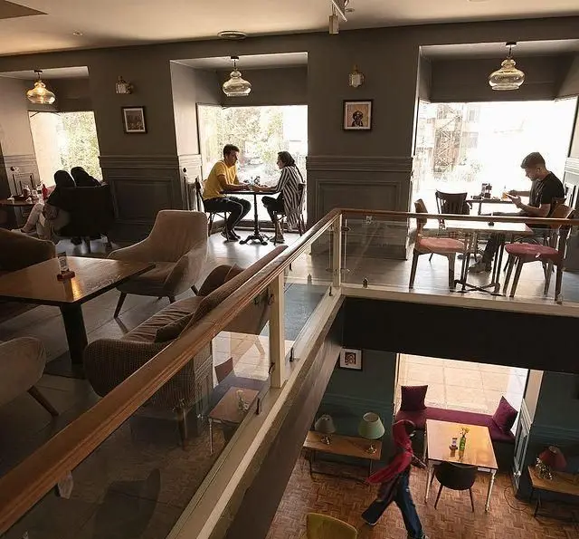 فضای داخلی روشن و دلنشین کافه قنادی بیترسوییت با دکوراسیون مدرن، شامل بخش‌های مختلف و مشتریانی در حال لذت بردن از محیط دنج.