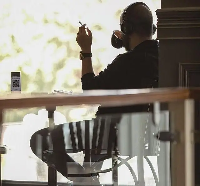 مشتری کافه قنادی بیترسوییت، با هدفون و فنجان قهوه، در حال لذت بردن از لحظه‌ای آرام کنار پنجره دنج کافه.