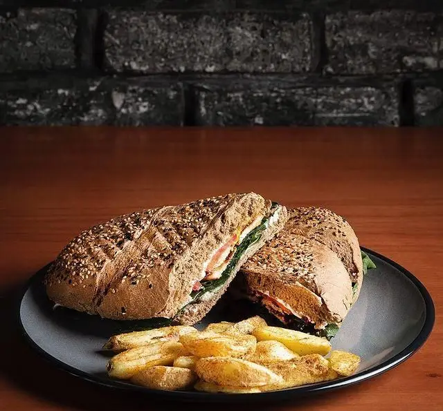 ساندویچ کامل نان غلات با مخلفات تازه و سیب زمینی وِج ترد، تجربه‌ای لذیذ از کافه قنادی بیترسوییت برای ناهار.