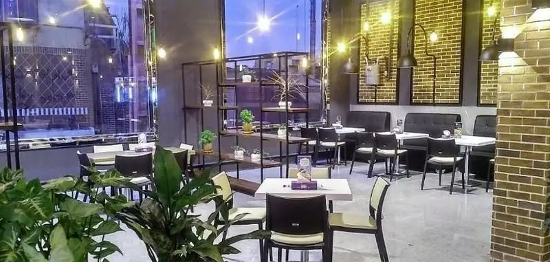 تصویری از فضای داخلی دنج و مدرن فست فود سیب360، با میز و صندلی‌های راحت، دکوراسیون جذاب و نورپردازی آرامش‌بخش.