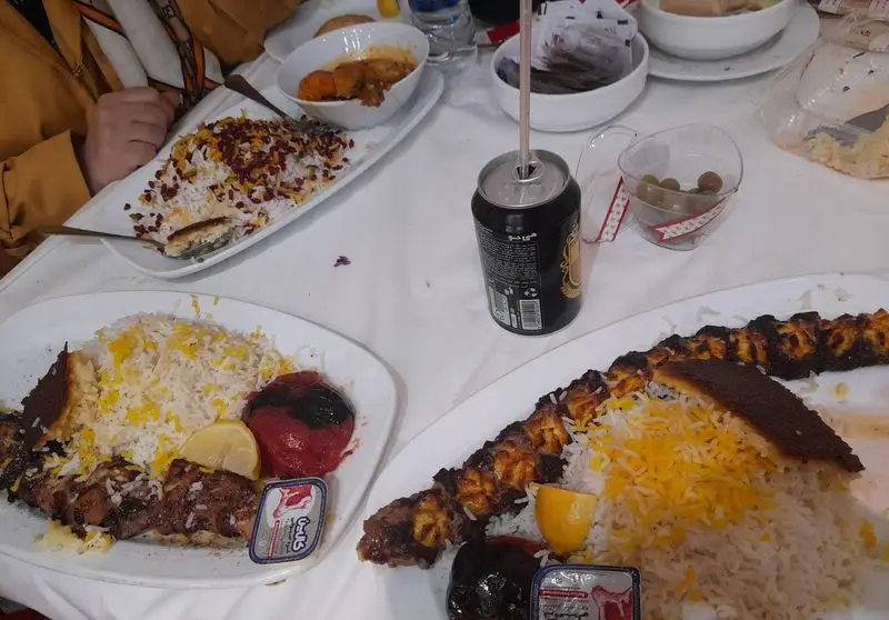 میز پر از غذا در رستوران هانی مرکزی: انواع چلوکباب، زرشک پلو زعفرانی، ته دیگ طلایی و خورش.