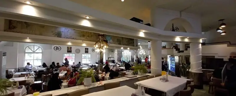 تصویری وسیع از سالن غذاخوری رستوران هانی مرکزی با ده‌ها مشتری در حال لذت بردن از غذا. فضایی دلنشین و خانوادگی برای تجربه آشپزی ایرانی.