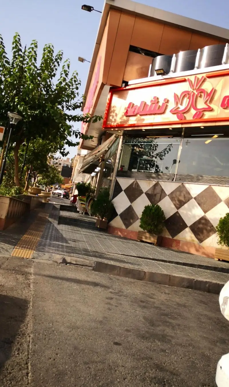 نمای بیرونی اغذیه نشاط، محلی برای انواع غذا و خوراک، با تابلوی بزرگ و طراحی شطرنجی جذاب در خیابان شهر.