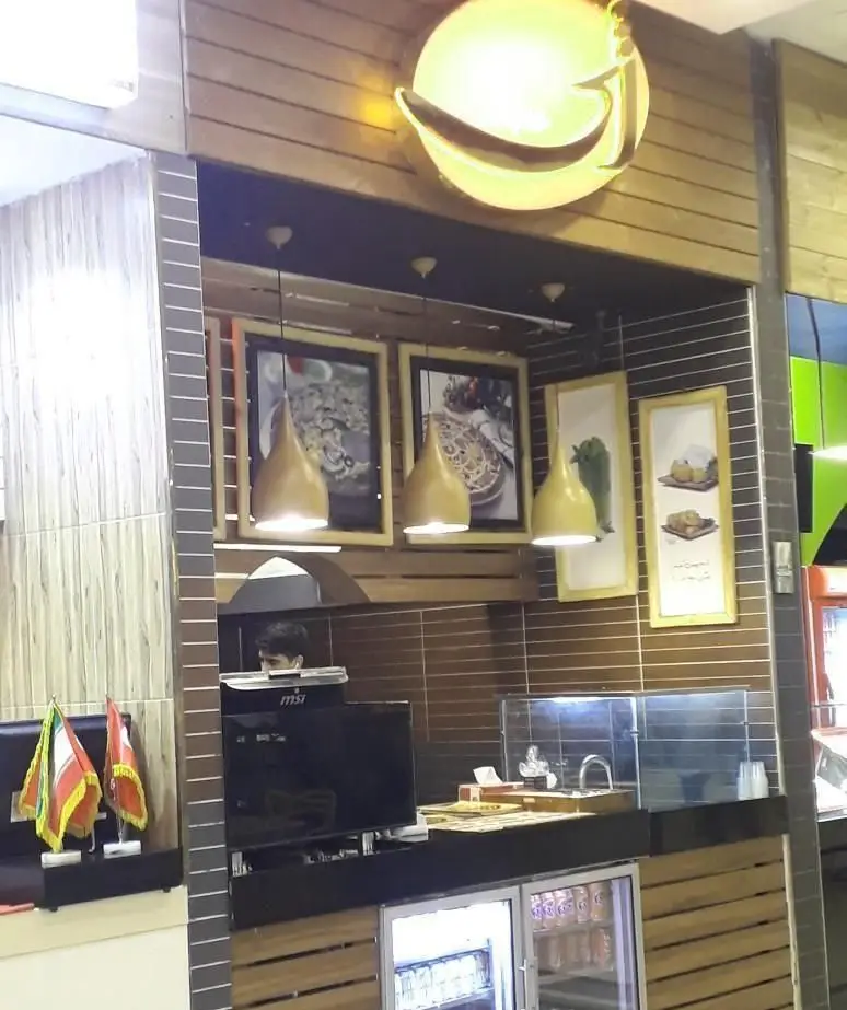 نمای داخلی فست فود ژی، دارای دکوراسیون چوبی گرم و مدرن، تابلوهای جذاب غذایی، چراغ‌های آویز و کانتر پذیرش سفارش مشتریان.