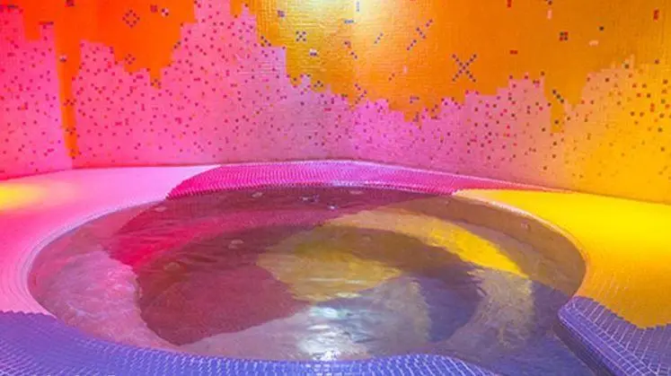 استخر روباز آفتاب: جکوزی رنگارنگ مدرن با کاشی‌های موزاییکی صورتی، نارنجی و زرد، فضایی زیبا و دلنشین برای آرامش و تفریح.
