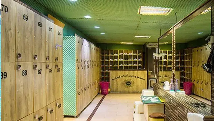 تصویر رختکن تمیز و مرتب مجموعه ورزشی و استخر روباز آفتاب کرمان، با کمدهای چوبی شماره‌گذاری شده و فضای مناسب برای بازدیدکنندگان.