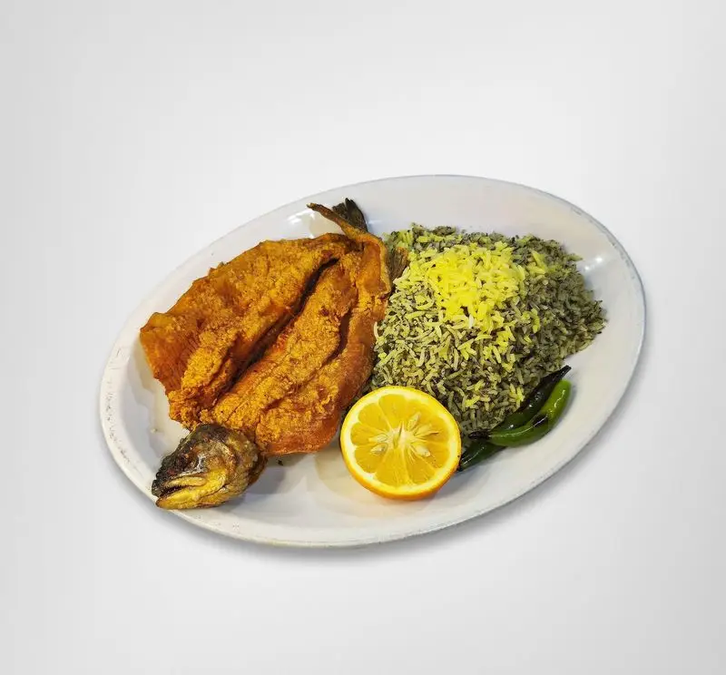 غذای لذیذ سبزی پلو با ماهی سرخ شده طلایی و لیمو تازه، یک پرس کامل و اشتهاآور در رستوران امینی.