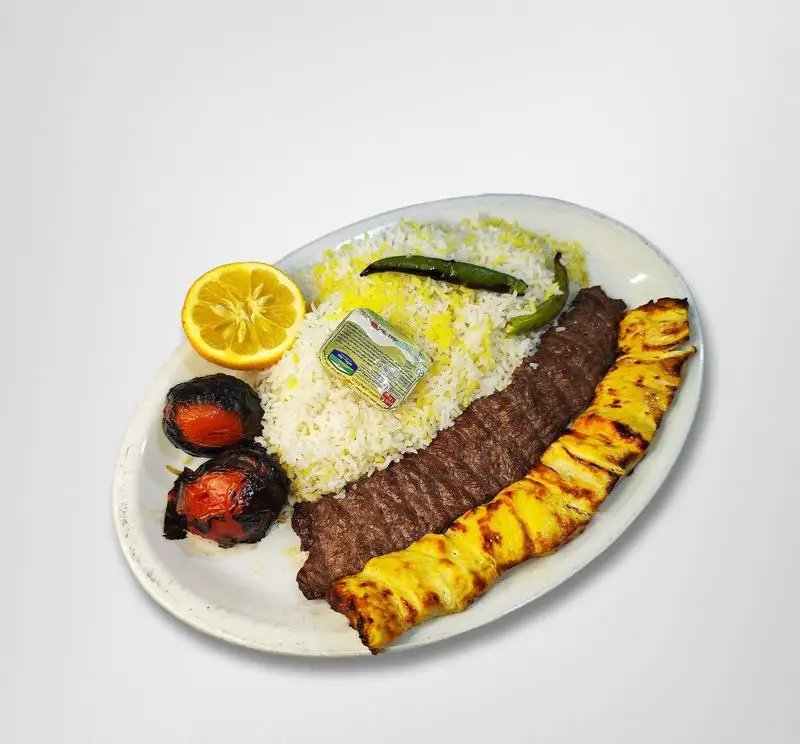 غذای کامل چلو کباب کوبیده و جوجه در رستوران امینی شامل برنج زعفرانی، کره، لیمو، گوجه کبابی و فلفل سبز تند، یک وعده لذیذ ایرانی