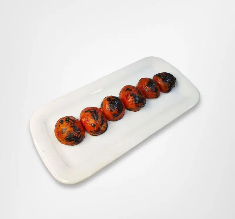 شش عدد گوجه فرنگی کبابی و بریان شده با پوست کمی سوخته و رنگ قرمز جذاب، روی دیس سفید رستوران امینی. مخلفات عالی غذا.