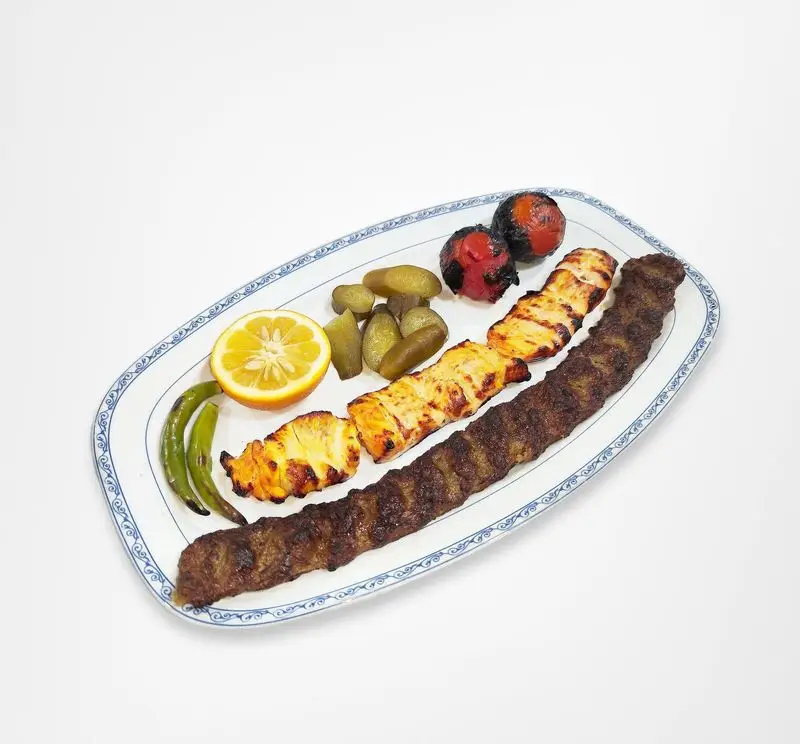 سینی کباب کوبیده و جوجه کباب رستوران امینی. کباب‌های لذیذ و گریل شده با مخلفات گوجه، لیمو، خیارشور و فلفل. بهترین غذای ایرانی.