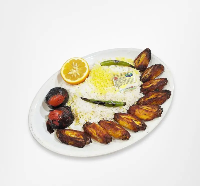 چلو بال و بازو کبابی لذیذ و طلایی از رستوران امینی، با برنج زعفرانی، گوجه و فلفل کبابی و لیمو تازه کنار کره.